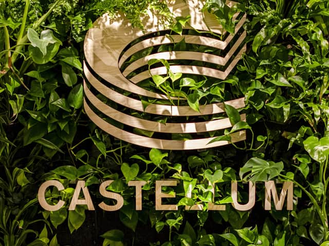 A Castelllum sign against a green wall.